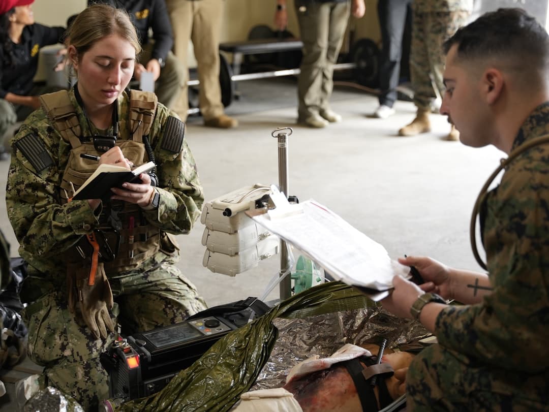 Two soldiers practice medical procedures with equipment.